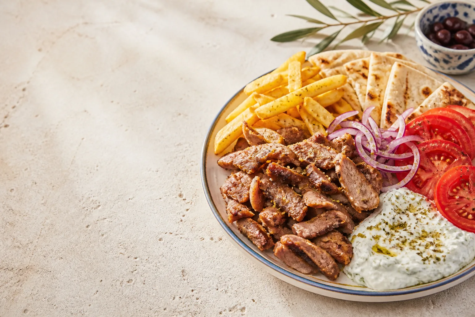 Greek gyros plate with pita, tzatziki, fries and fresh vegetables