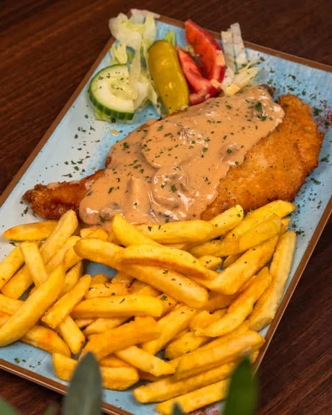 Schnitzel with sauce, fries and salad at Zaki’s